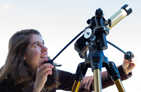 girl looking through a telescope